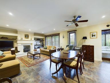 A living room with sofas coffee table dining table and ceiling fan at Rokeby in Bamburgh