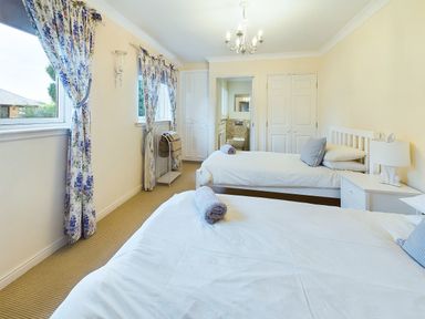 A bedroom with two single beds white bedding and floral curtains at Rokeby in Bamburgh