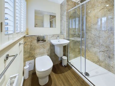 A bathroom with a toilet, sink, shower enclosure, and a wall-mounted mirror at Rokeby Bamburgh
