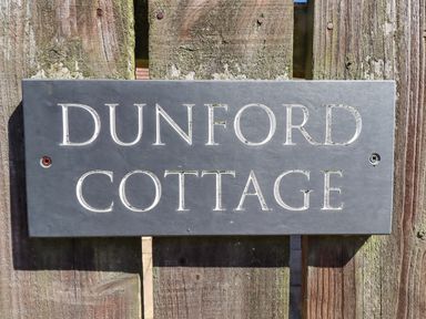 A nameplate reading Dunford Cottage on a wooden fence in Bamburgh
