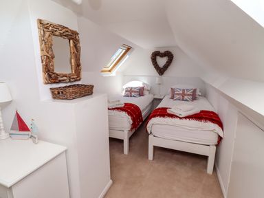 A bedroom with twin beds and a decorative mirror at Dunford Cottage Bamburgh