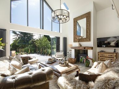 A living room with leather sofas a wooden coffee table a fireplace and large windows at Marmalade Cottage in Seahouses