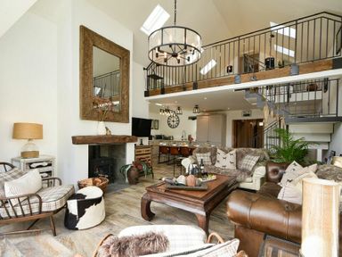 An open living room with a fireplace wooden coffee table sofas armchairs and a mezzanine at Marmalade Cottage in Seahouses