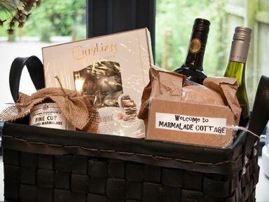 A basket with wine bottles chocolates marmalade and a welcome sign at Marmalade Cottage in Seahouses