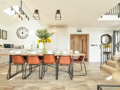 A dining area with a wooden table set with dishes and sunflowers in a vase at Marmalade Cottage in Seahouses