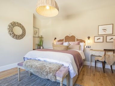 A bedroom with a bed a bench a desk and wall decorations at Marmalade Cottage in Seahouses