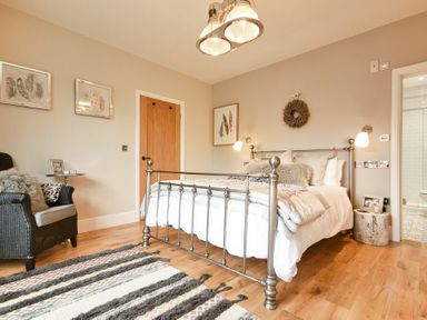 A bedroom with a metal bed frame a chair a wooden door and a striped rug at Marmalade Cottage in Seahouses