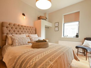 A bedroom with a bed a chair a window and a light fixture at Marmalade Cottage in Seahouses