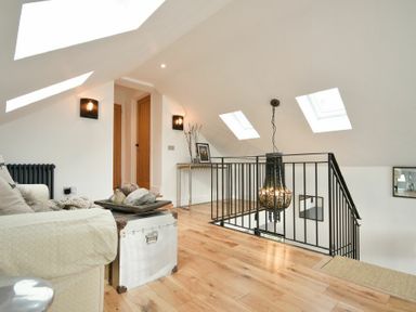 An attic living space with a sofa a chest coffee table wooden floors skylights and a hanging light at Marmalade Cottage in Seahouses