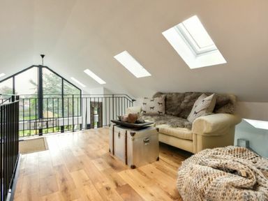 A sitting area with a couch a metal chest used as a table and skylights in an attic space at Marmalade Cottage in Seahouses