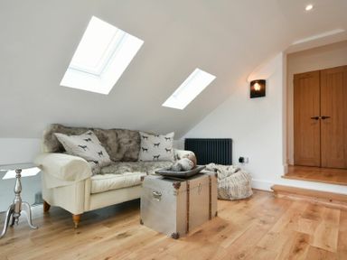 A sitting area with a sofa with cushions and a metal trunk coffee table under skylights at Marmalade Cottage in Seahouses
