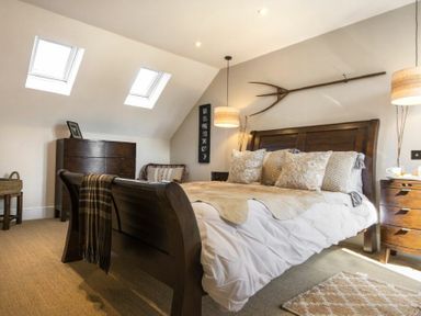 A bedroom with a wooden bed, dresser, chair, and two skylights at Marmalade Cottage in Seahouses