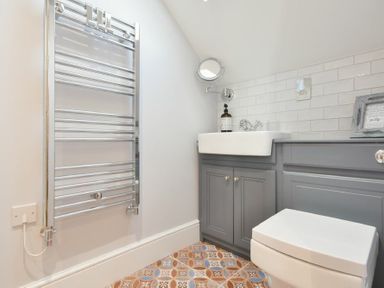 A bathroom with a towel radiator sink with cabinet and toilet at Marmalade Cottage in Seahouses
