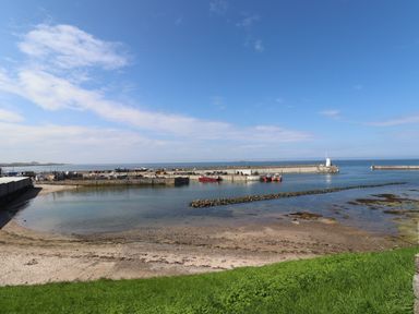 A harbor with boats docked and a small lighthouse at Anchor Cottage Seahouses
