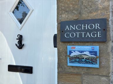 A door with a nameplate and a sign at Anchor Cottage in Seahouses