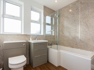 A bathroom with a toilet sink and bathtub with glass shower screen at Church View in Bamburgh