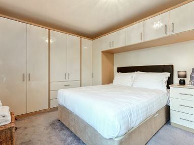 A bedroom with a double bed white wardrobes and a bedside table with a lamp at Annstead House in Seahouses