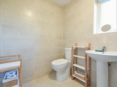 A bathroom with a toilet sink a wooden shelf and a window at Annstead House in Seahouses
