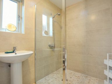 A bathroom with a pedestal sink a glass shower enclosure and tiled walls at Annstead House in Seahouses
