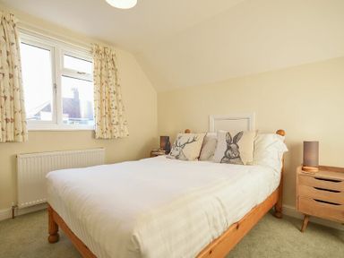 A bedroom with a wooden bed and animal print cushions beside a window at Annstead House in Seahouses