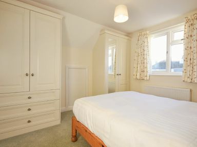 A bedroom with a bed a window with curtains and built in wardrobes at Annstead House in Seahouses
