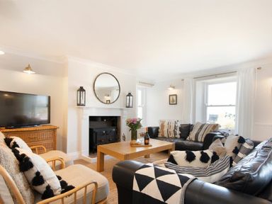A living room with black leather sofas a wooden coffee table a fireplace and a television at Cargoes in Craster