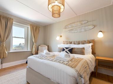 A bedroom with a double bed and rolled towels on it next to a window with curtains at Cargoes in Craster