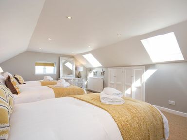 A bedroom with three single beds under skylights and a dresser at Cargoes in Craster