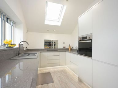 A kitchen with white cabinets grey countertops an oven a sink and a skylight at Viewpoint in Alnmouth