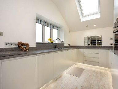 A kitchen with white cabinets and gray countertops under a skylight at Viewpoint in Alnmouth