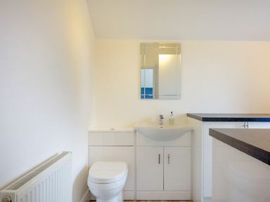 A bathroom with a toilet sink cabinet and mirror at Viewpoint in Alnmouth