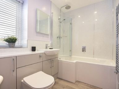 A bathroom with a toilet sink cabinet bathtub with shower and a window with blinds at Viewpoint in Alnmouth