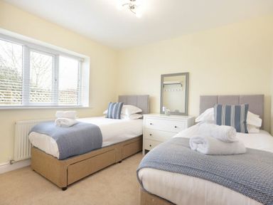 A bedroom with two single beds a white chest of drawers and a window at Viewpoint in Alnmouth