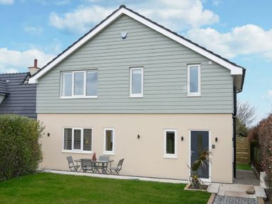 A backyard with a metal table and chairs next to a two-story house with multiple windows at Viewpoint in Alnmouth