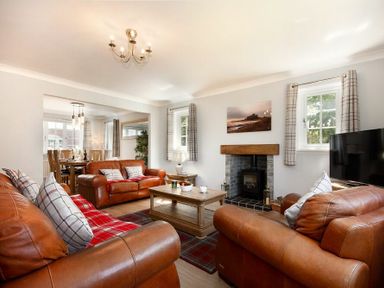 A living room with brown leather sofas a wooden coffee table a fireplace and a television at Castlewood in Bamburgh