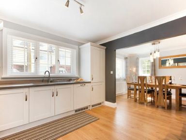 A kitchen with white cabinets and a sink next to a dining room with a wooden table and chairs at Castlewood in Bamburgh