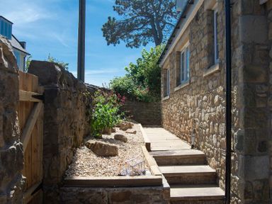 A stone walled path with stairs and a garden bed with rocks and plants at Castlewood in Bamburgh