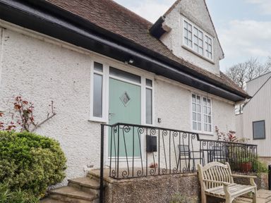 The exterior of a house with a green front door black metal railings and outdoor seating at Rosedale Lodge in Alnmouth