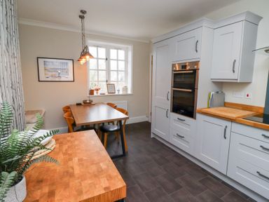 A kitchen with wooden countertops and dining table with chairs at Rosedale Lodge in Alnmouth