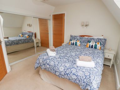 A bedroom with a double bed blue floral bedspread and mirrored wardrobes at Rosedale Lodge in Alnmouth