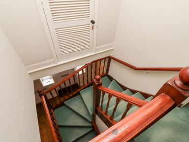 A staircase with green carpet and wooden handrails at Rosedale Lodge in Alnmouth
