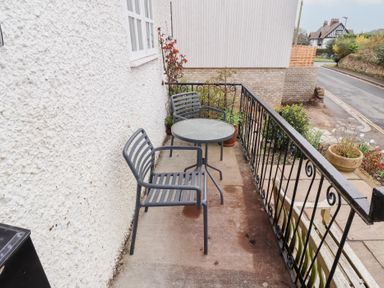 A small outdoor balcony with two metal chairs and a round table at Rosedale Lodge in Alnmouth