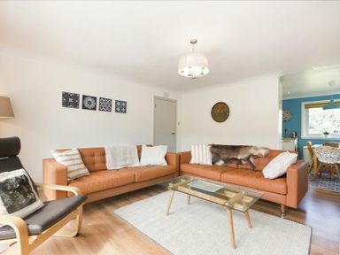 A living room with two brown leather sofas a glass coffee table and an armchair at Spuggies Rest in Embleton