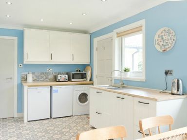 A kitchen with white cabinets a microwave toaster washing machine fridge sink and kettle at Spuggies Rest in Embleton