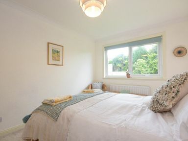 A bedroom with a bed pillows window chair and framed picture on the wall at Spuggies Rest in Embleton