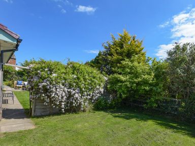 A garden with a lawn and flowering bushes next to a building at Spuggies Rest in Embleton