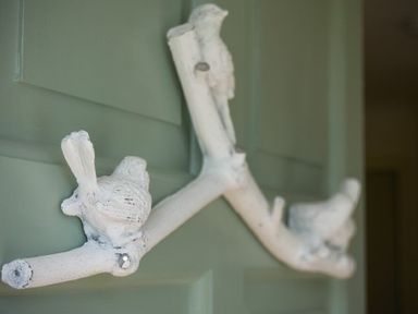 A white decorative bird and branch figure mounted on a green door at Spuggies Rest in Embleton