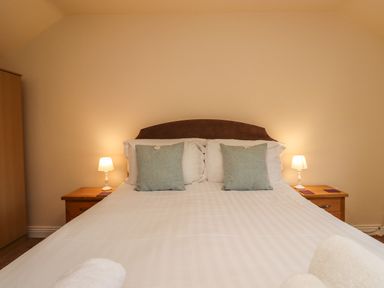 A bedroom with a bed with two pillows and bedside tables with lamps at Stewart House in Wooler