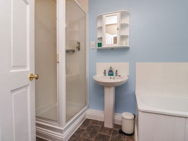 A bathroom with a shower cubicle sink with mirror cabinet and bathtub at Stewart House in Wooler