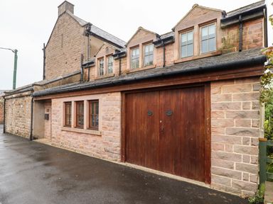 A stone building with three dormer windows and a wooden garage door in Wooler